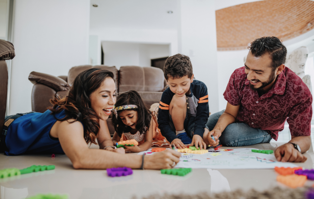 A family sitting on the floor playing with colorful blocks.