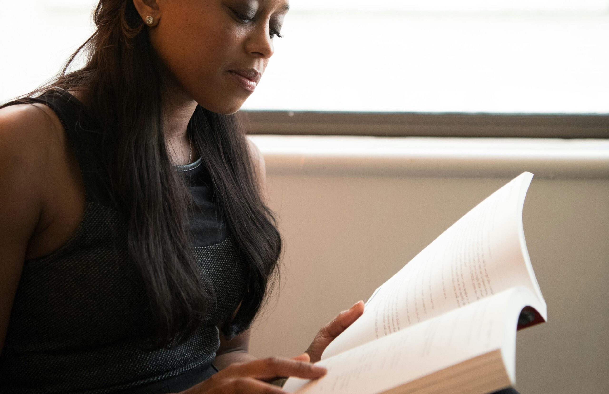 Adult woman reading by a window.